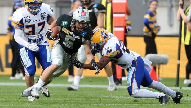 Ein American-Football-Spieler wird von einem Gegenspieler zu Fall gebracht.