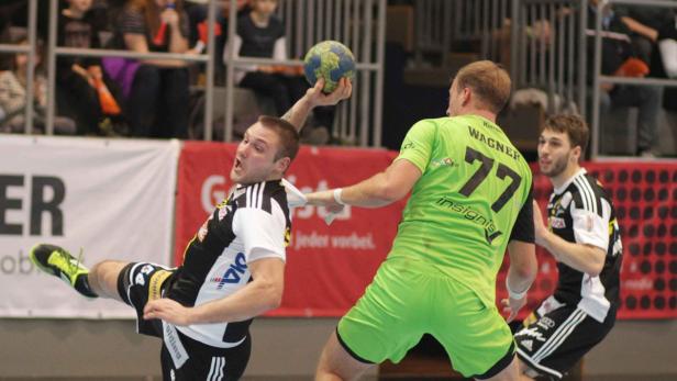 Ein Handballspieler wirft den Ball, während ein Gegenspieler ihn zu stoppen versucht.