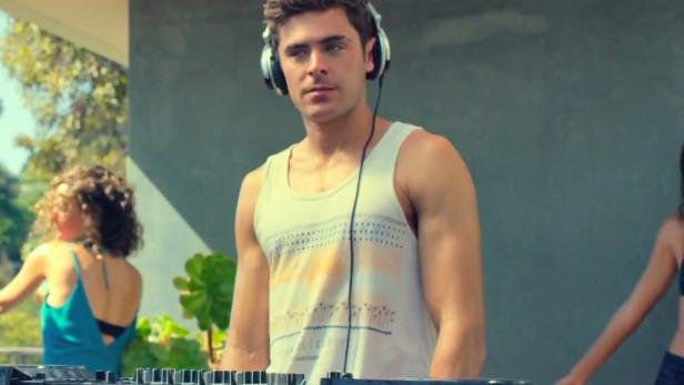 Zac Efron als DJ mit Kopfhörern an einem Pioneer-Mischpult.