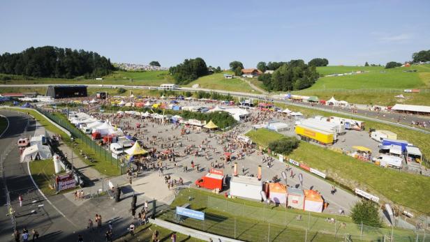 Eine große Menschenmenge versammelt sich auf einem Festivalgelände mit Bühne und Verkaufsständen.
