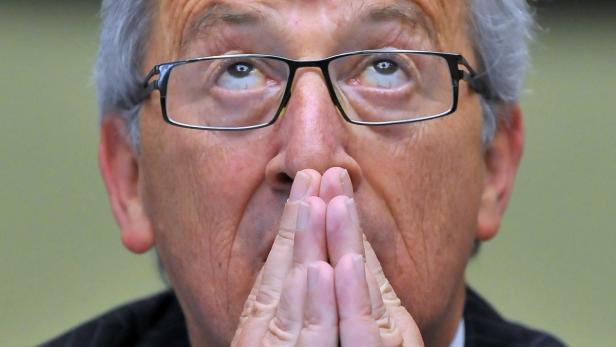 Jean-Claude Juncker blickt mit gefalteten Händen nach oben.