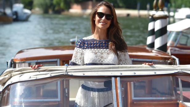 Eine Frau mit Sonnenbrille steht auf einem Boot in Venedig.