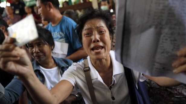 Mit Tränen in den Augen bettelt eine Frau in Bangkok vor dem verschlossenen Wahlbüro um ihr Wahlrecht.