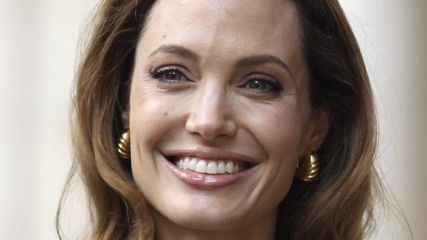 Nahaufnahme von Angelina Jolie, die lächelt und goldene Ohrringe trägt.