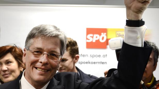 Ein lächelnder Mann mit Brille und erhobener Faust vor einem SPÖ-Logo.