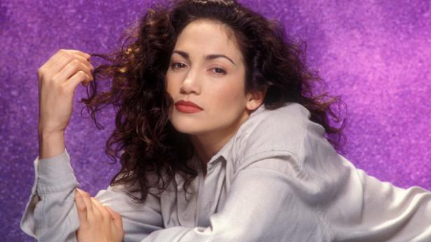 Jennifer Lopez posiert vor einem lila Hintergrund.
