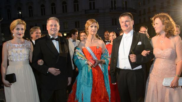 Gäste in Abendgarderobe posieren vor einem Gebäude für ein Foto.