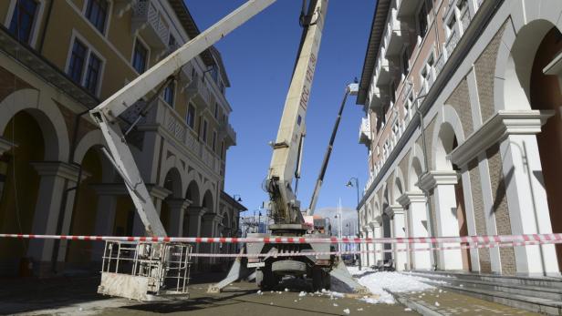 Eine Hubarbeitsbühne steht auf einer Straße zwischen Gebäuden mit Arkaden.