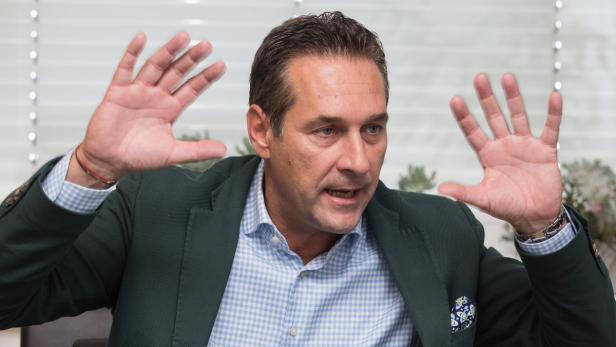 Ein Mann in einem grünen Sakko gestikuliert mit erhobenen Händen.