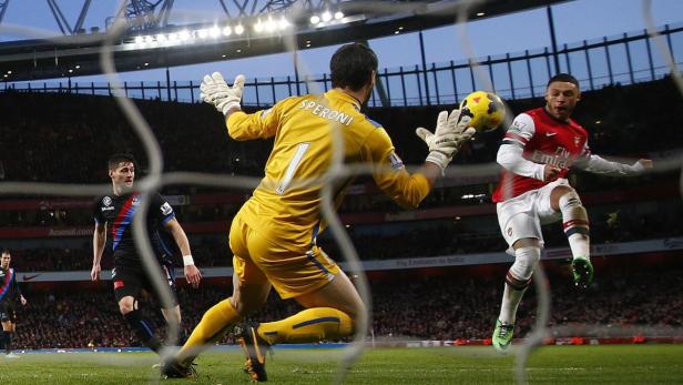 Ein Fußballspieler von Arsenal schießt auf das Tor, während der Torwart von Crystal Palace versucht, den Ball abzuwehren.