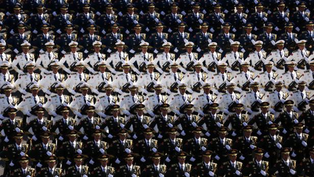 Eine Parade von Soldaten in verschiedenen Uniformen marschiert in Reih und Glied.