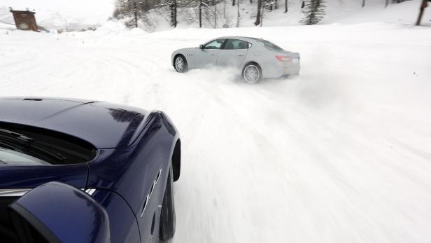 Ein silberner Maserati fährt auf einer schneebedeckten Straße, gefolgt von einem blauen Maserati.