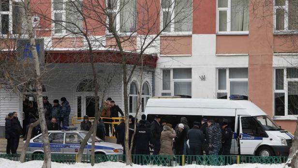Vor einem Gebäude in Moskau stehen Polizisten und ein Polizeiwagen.