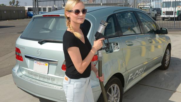 Eine Frau betankt ein hellblaues Mercedes-Benz F-CELL Wasserstoffauto.