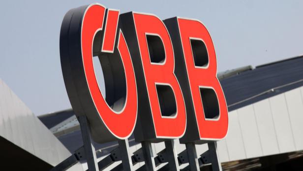 Das rote ÖBB-Logo vor einem Bahnhofsgebäude.