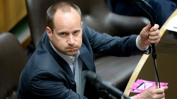 Ein Mann im Anzug hält ein Mikrofon in einem Konferenzraum.