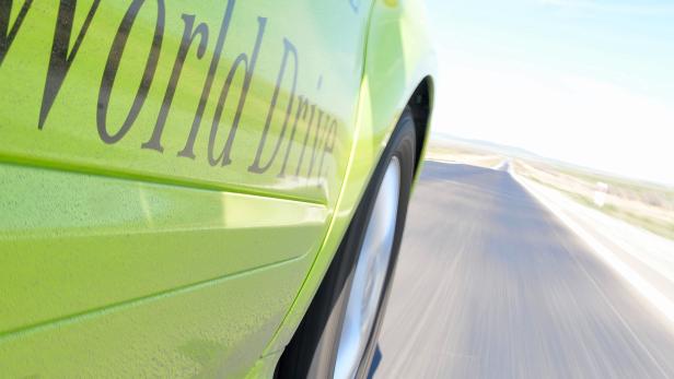 Ein grüner Mercedes-Benz „World Drive“ fährt auf einer Landstraße.