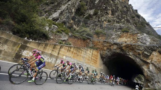 Eine Gruppe Radfahrer fährt auf einer Straße in der Nähe eines Tunnels.
