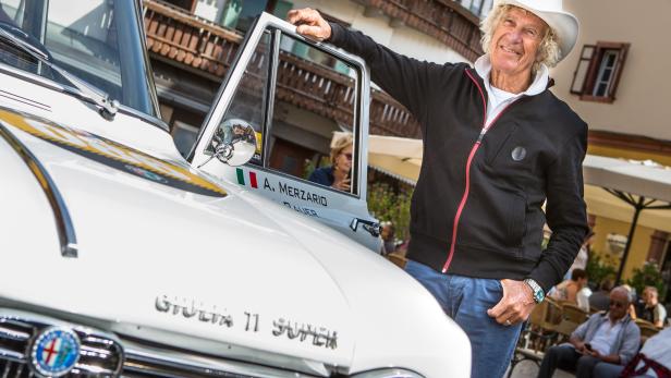 Ein Mann mit Cowboyhut posiert neben einem weißen Alfa Romeo Giulia 11 Super Oldtimer.