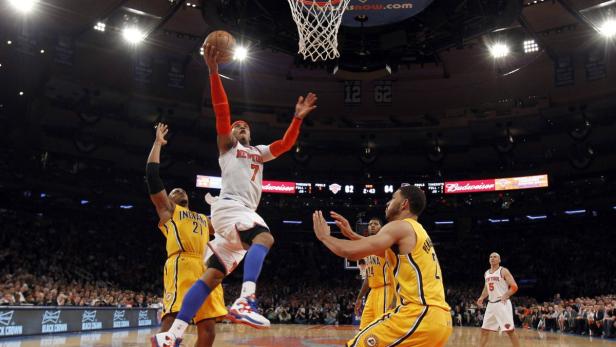 Ein Basketballspieler der New York Knicks wirft den Ball auf den Korb, während Gegenspieler ihn zu verteidigen versuchen.