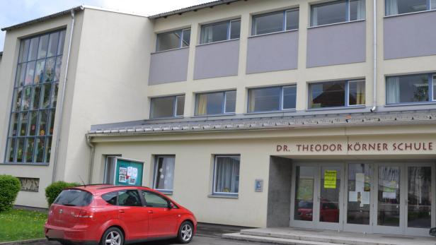 Die Dr. Theodor Körner Schule mit einem roten Auto davor.