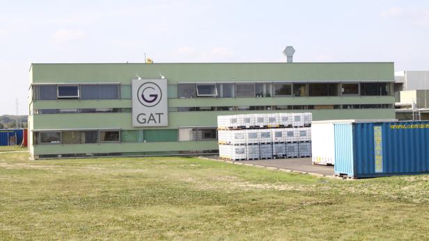 Das GAT-Gebäude mit Containern und gestapelten IBC-Containern im Außenbereich.