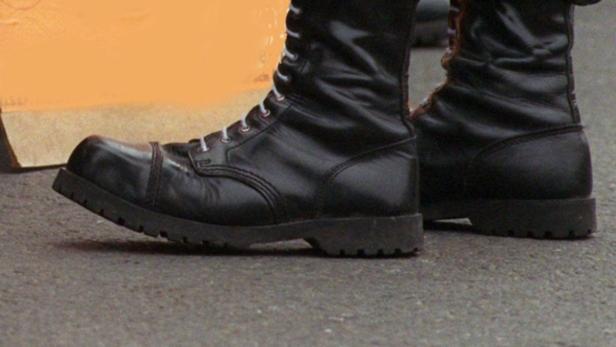Wenn Stiefel zu Waffen werden, gibt's schwere Folg… Ein Paar schwarze Springerstiefel stehen auf dem Asphalt.
