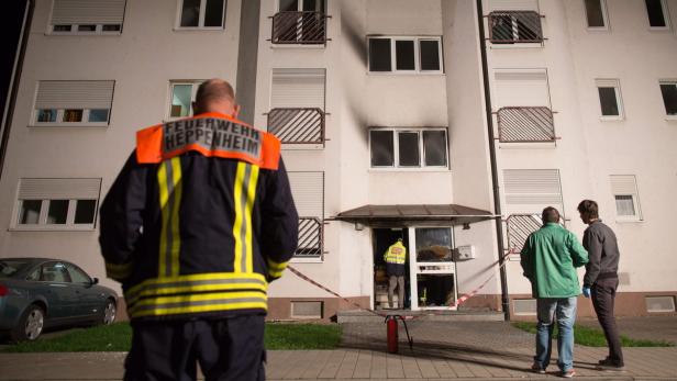 Feuerwehrleute stehen vor einem Wohnhaus mit Brandschaden in Heppenheim.