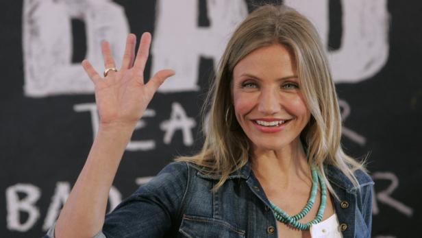 Cameron Diaz lächelt und winkt vor einer Tafel für den Film „Bad Teacher“.