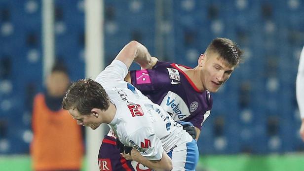 Zwei Fußballspieler kämpfen um den Ball während eines Spiels.
