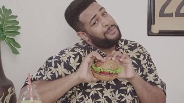 Ein Mann mit Bart hält einen Burger in seinen Händen.
