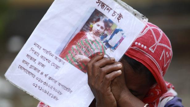 epa03691607 A woman cries holding the photo of her missing daughter on the thirteenth day of the Rana Plaza building collapse, in Savar, Dhaka, Bangladesh, 08 May 2013. Reports state that the death toll rose over 766 and many more still missing, according to the rescue control room by the military officials leading rescue operations at the spot. 588 bodies were handed over to their relatives after identification after the eight-storey building Rana Plaza housed mostly garment factories which collapsed on 24 April 2012. EPA/ABIR ABDULLAH