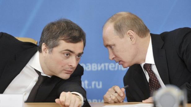 Wladimir Putin im Gespräch mit einem Mann am Tisch.