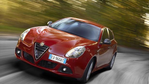 Ein roter Alfa Romeo Giulietta fährt auf einer kurvigen Straße.