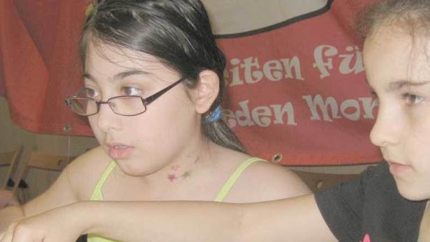 Zwei Mädchen sitzen an einem Tisch und schauen aufmerksam auf einen Bildschirm.