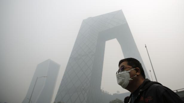 A man wearing a mask walks on a street during a hazy day in Beijing October 10, 2014. Widespread smog has affected a large part of north China including capital Beijing as the National Meteorological Center (NMC) extended a yellow alert on Thursday for air pollution, Xinhua News Agency reported. REUTERS/Kim Kyung-Hoon (CHINA - Tags: ENVIRONMENT TPX IMAGES OF THE DAY)