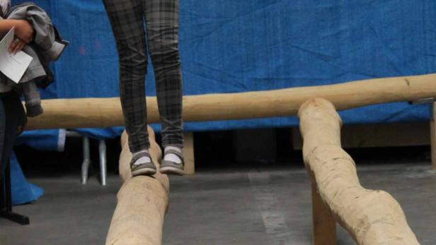 Ein junges Mädchen balanciert auf einem Baumstamm.