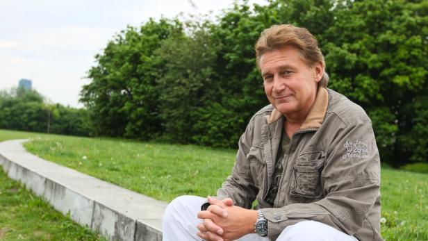 Ein Mann sitzt auf einer Mauer in einem Park.