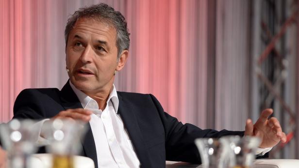 Ein Mann in Anzug gestikuliert während einer Präsentation.