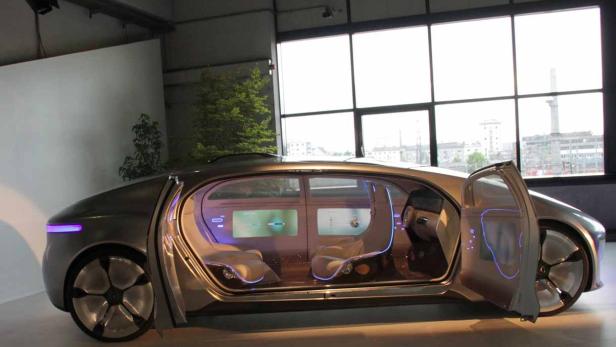 Ein futuristisches Auto mit geöffneter Tür steht in einem Ausstellungsraum.