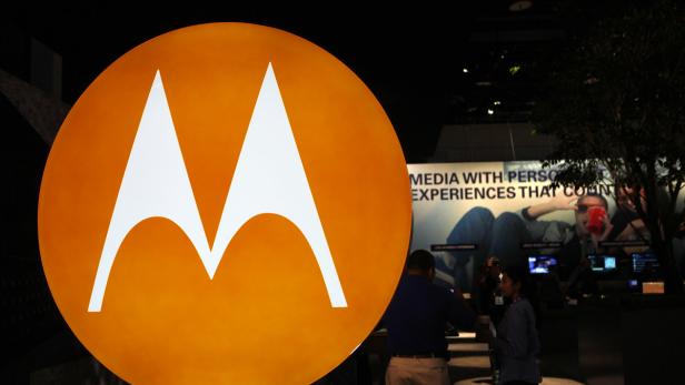 Das Motorola-Logo vor einem Stand mit Bildschirmen und Personen.