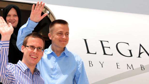 Drei Personen winken aus der Tür eines Embraer Legacy Privatjets.