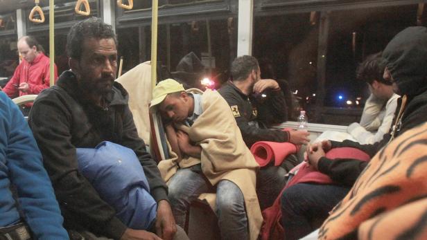 Mehrere müde Menschen sitzen in einem Bus.