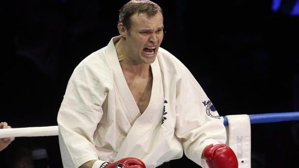 Ein Karatekämpfer mit roter Boxhandschuhen schreit in einem Kampf.