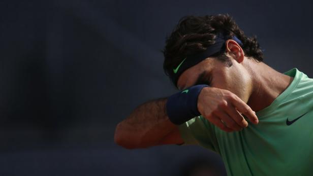 Ein Tennisspieler wischt sich den Schweiß von der Stirn.