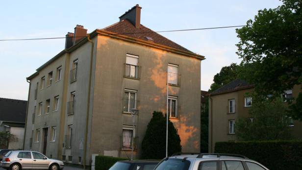 Ein Mehrfamilienhaus mit mehreren Balkonen im Abendlicht.