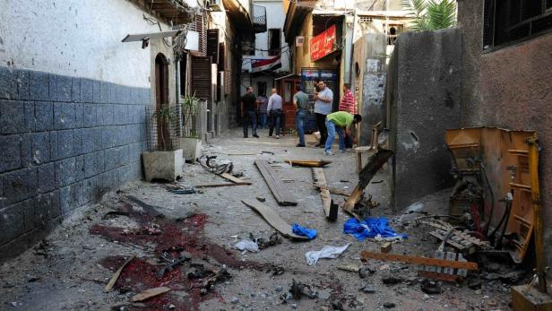 Nach einem Bombenanschlag liegen Trümmer und Blut auf einer Straße in Syrien.
