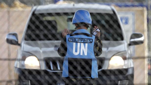A Filipino United Nations peacekeeper directs a car at the Kuneitra border crossing between Israel and Syria, in the Israeli occupied Golan Heights March 9, 2013. REUTERS/Baz Ratner (ISRAEL - Tags: POLITICS CIVIL UNREST)