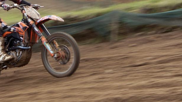 Ein Motocross-Fahrer rast auf einer schlammigen Strecke entlang.