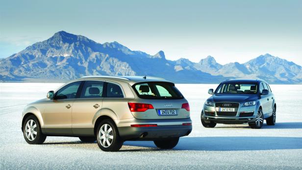 Zwei Audi Q7 SUVs stehen vor einer Bergkulisse.
